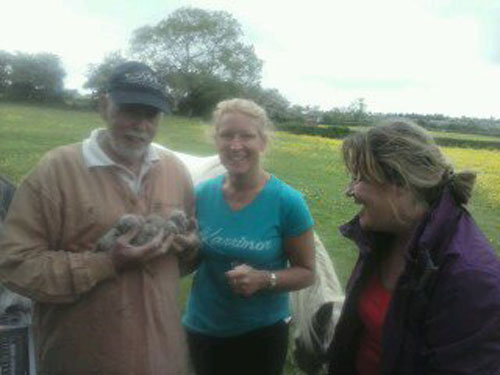 Howard holding several little owls with two smiling ladies looking on
