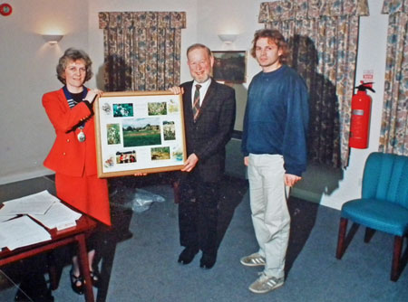 Linda Abbey, Ken Jackson holding a framed collage of meadow photos with Peter Meade